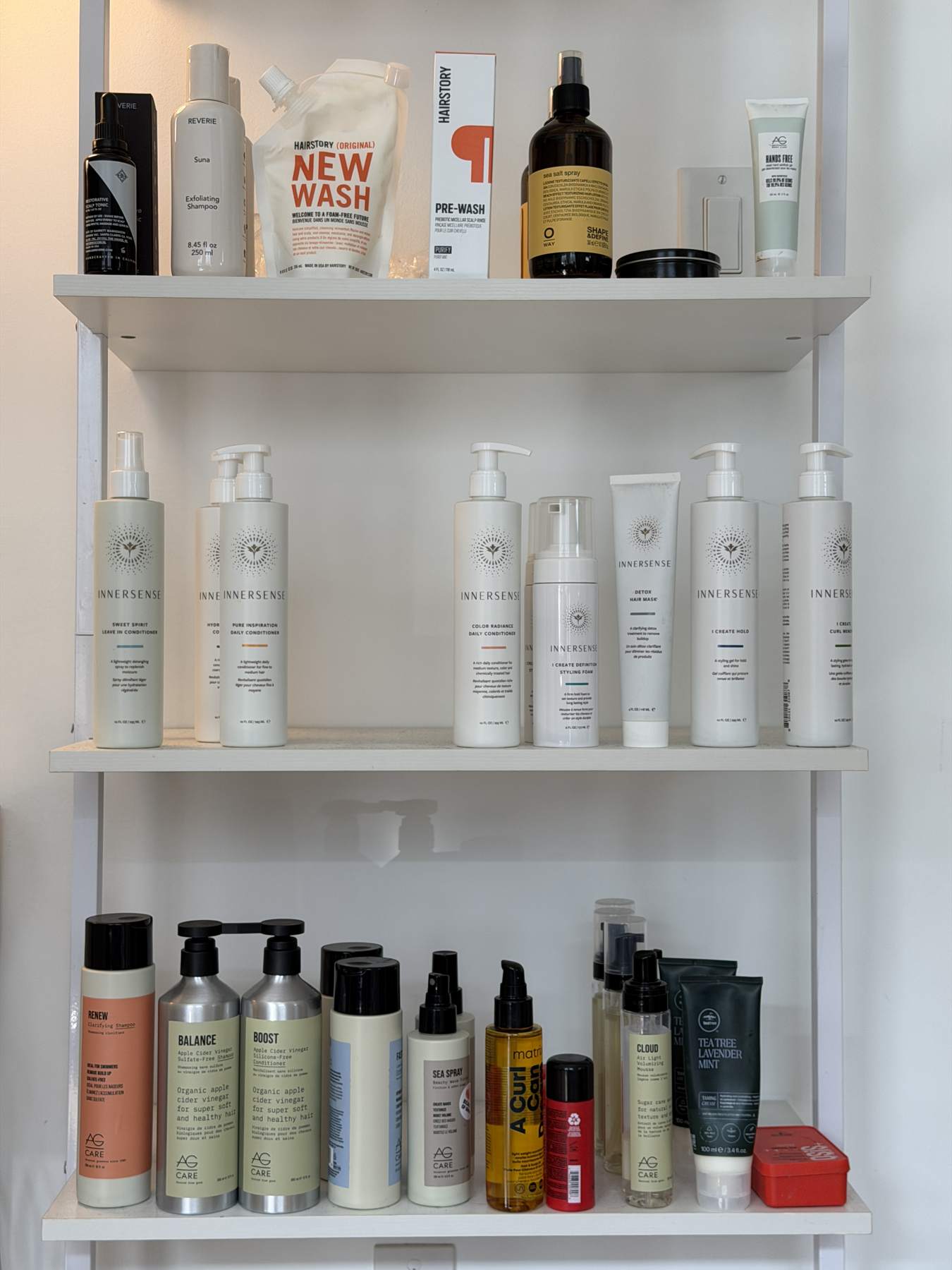 White wall shelves holding rows of hair care bottles