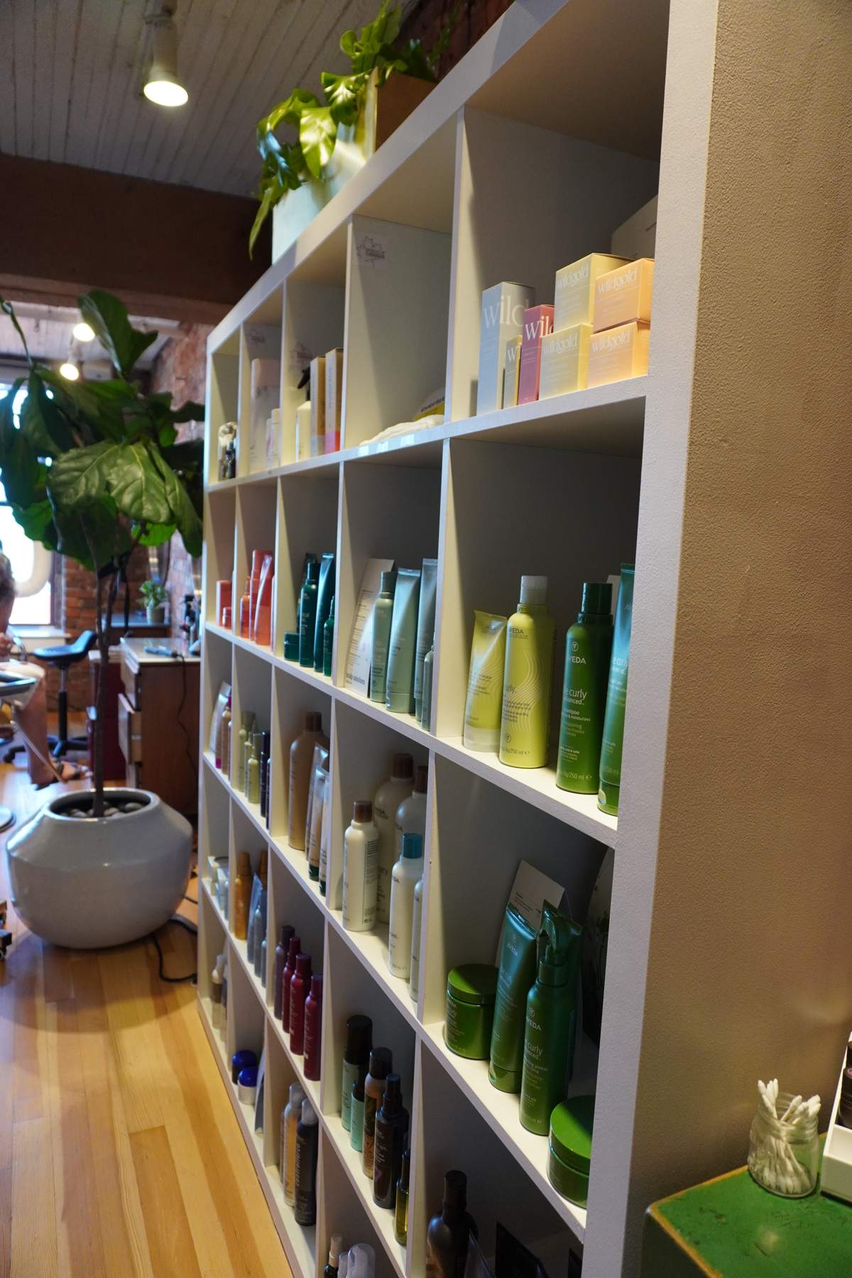Tall white shelves filled with hair care products in a salon