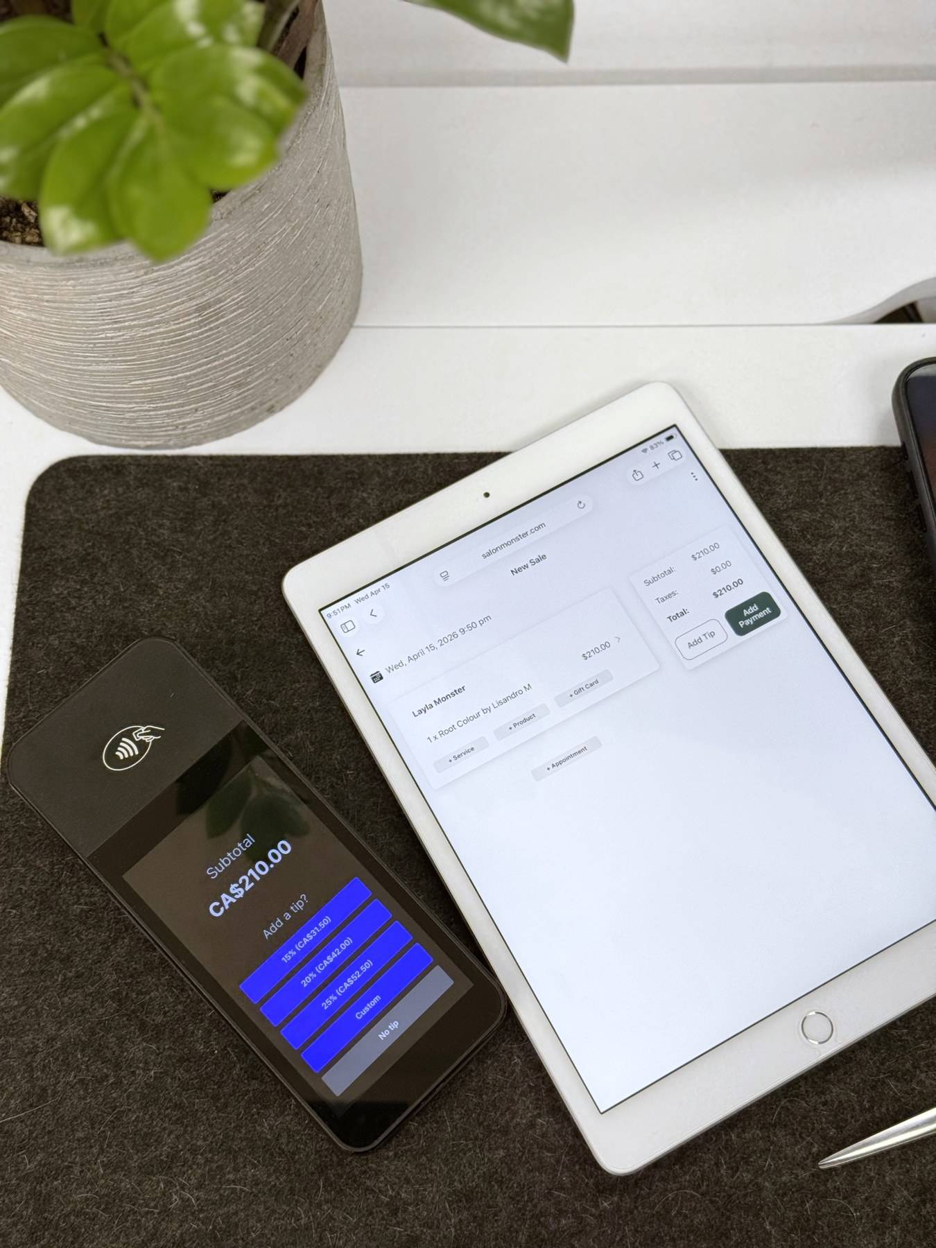 A card reader showing a sale total next to a tablet open on a checkout screen