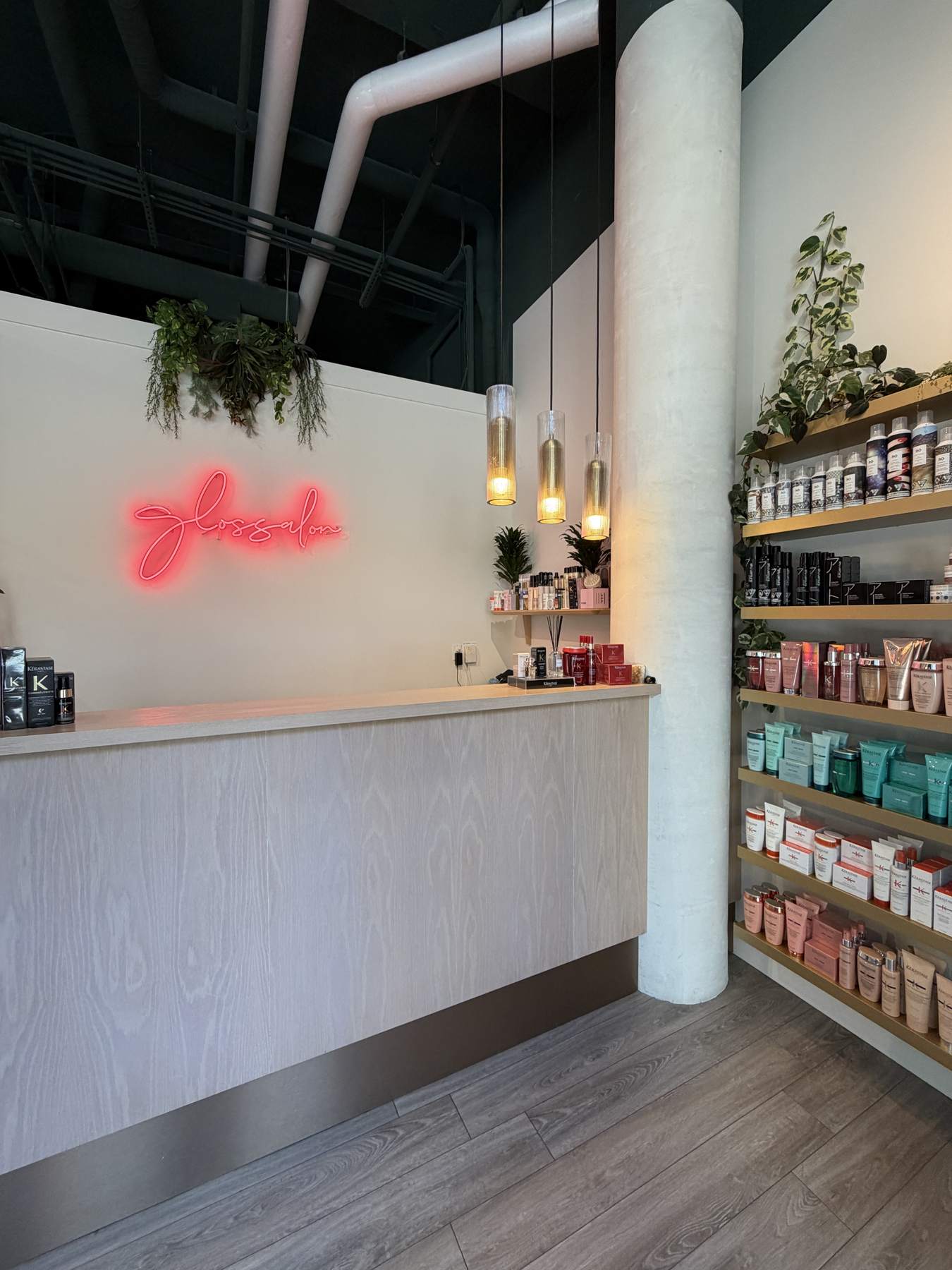 A salon reception desk with a pink neon sign and shelves of retail products