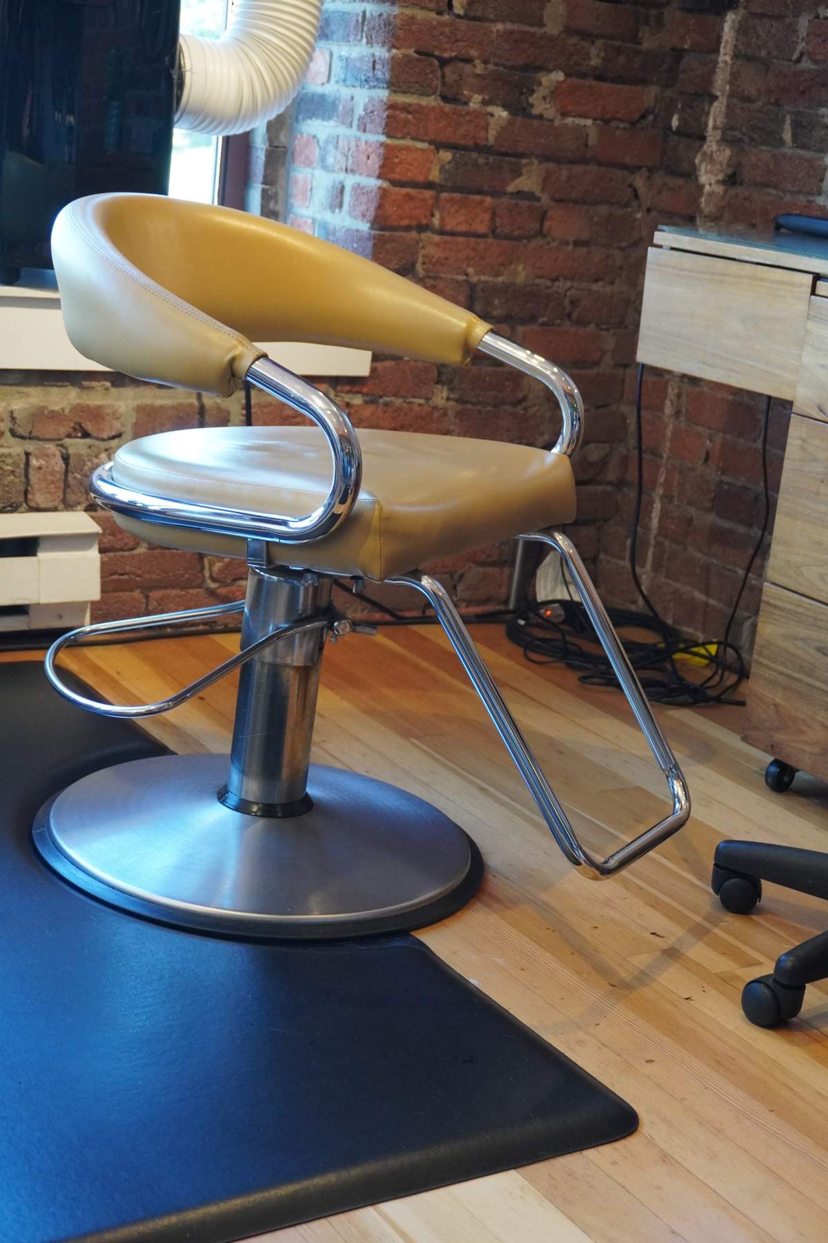An empty mustard-coloured styling chair at a station by a brick wall