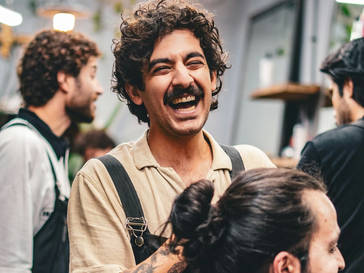 A laughing stylist on the floor of a busy salon, with colleagues working in the background