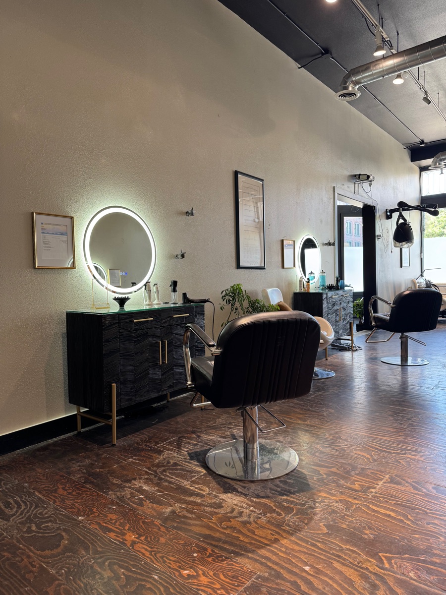 A salon styling station with a lit round mirror, cart, and chair